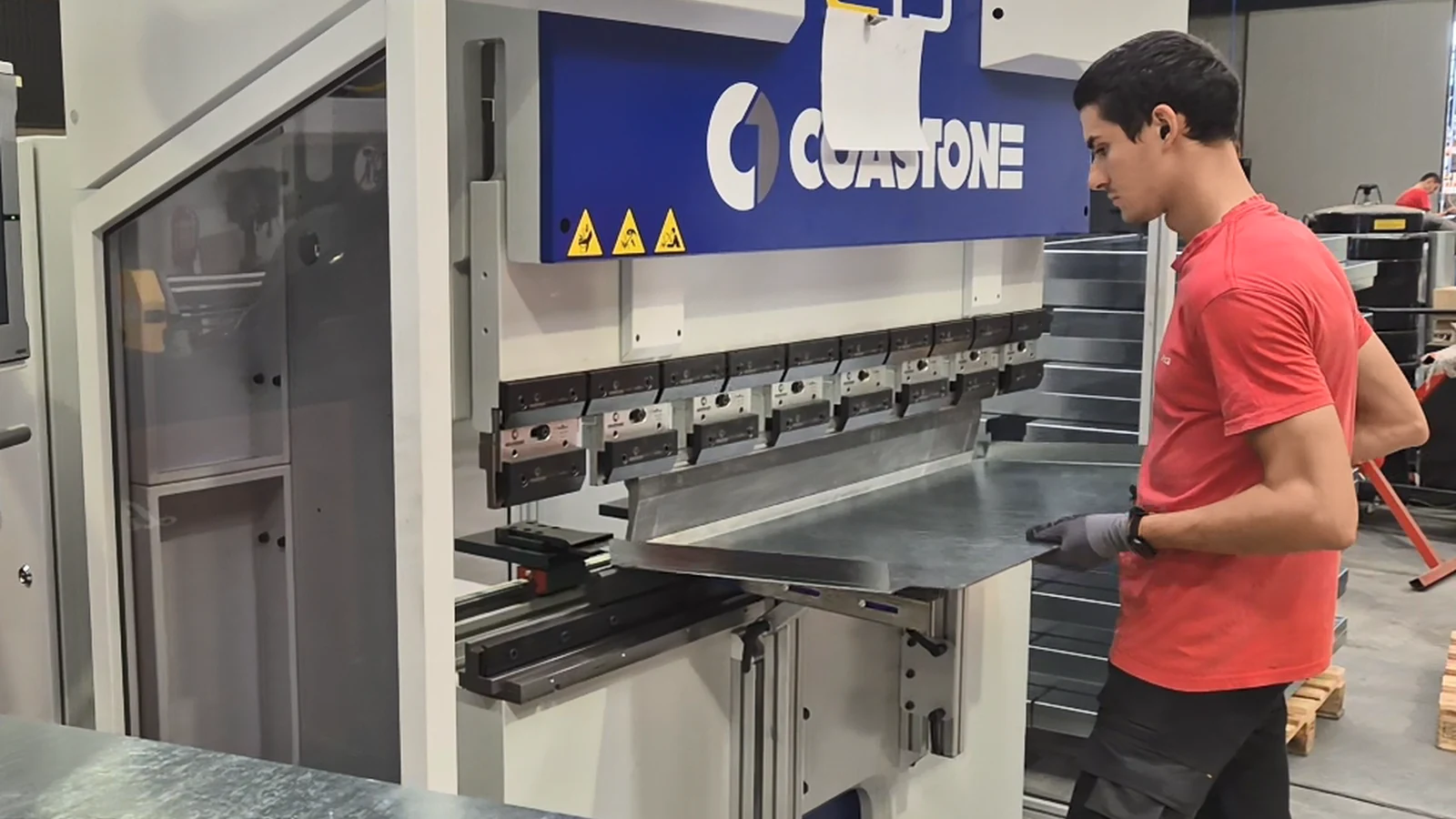An operator feeding a galvanised sheet metal blank into the CoastOne Cone C15 press brake