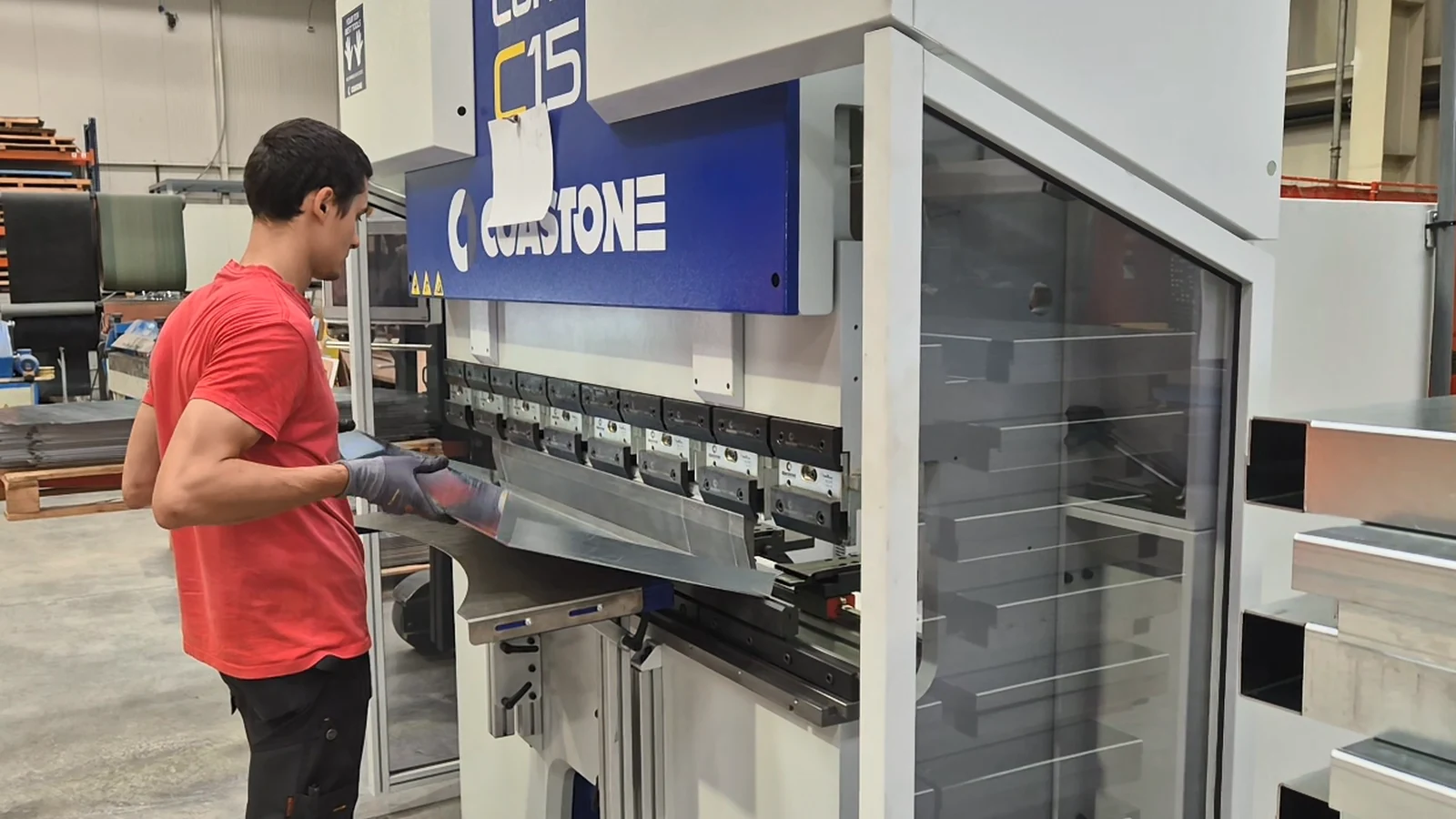 An operator holding a bent galvanised profile in the tooling of the CoastOne Cone C15