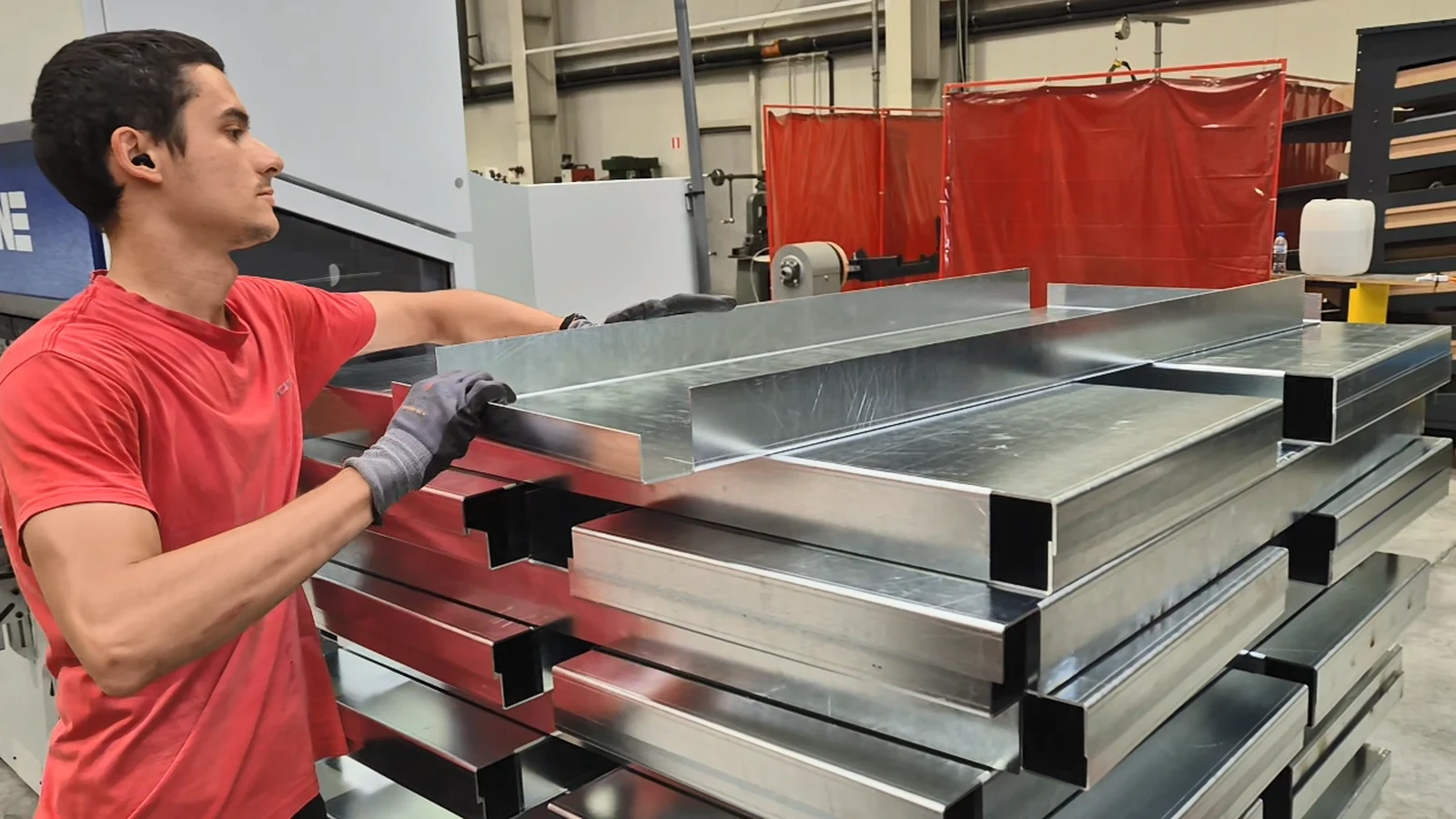 An operator stacking a finished bent profile on top of the rest of the same batch