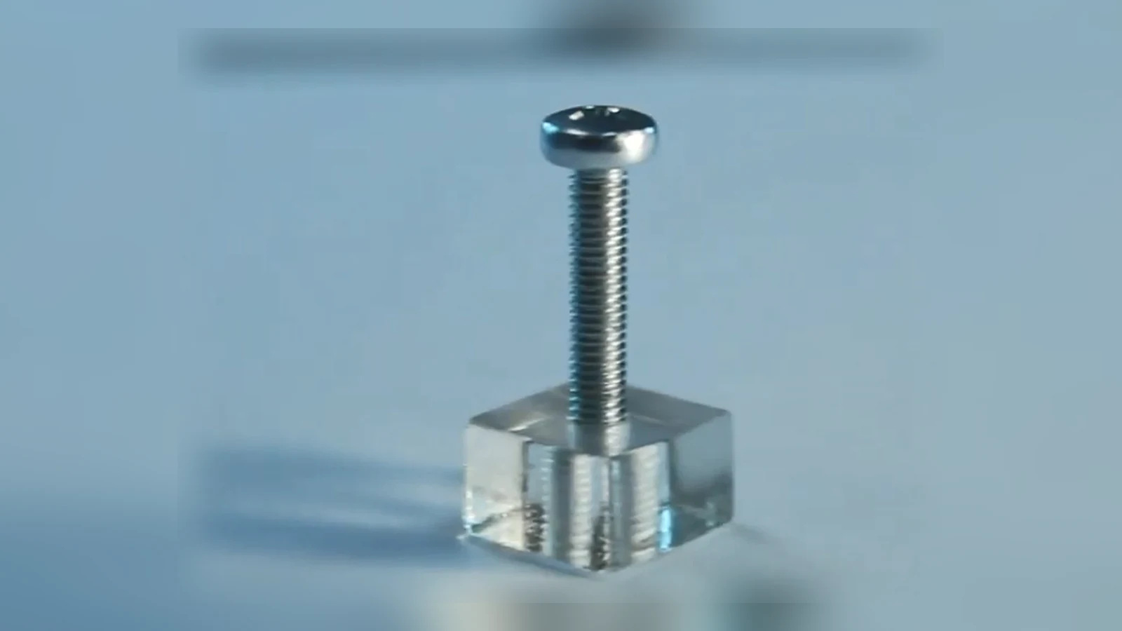 A metal screw fastened into a thread cut in an acrylic cube