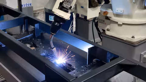 The robot's welding torch working inside a dark enclosure, sparks around it