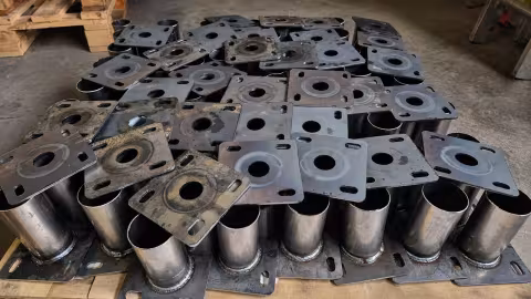 A pallet of finished welded parts — tubes with square flanges welded on