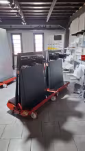 Two NEON SMART trolleys coupled together and loaded with black panels, in a showroom